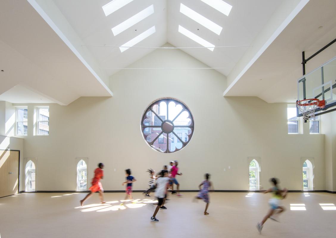 Gym interior showing vaulted church ceiling with skylights, and rose window